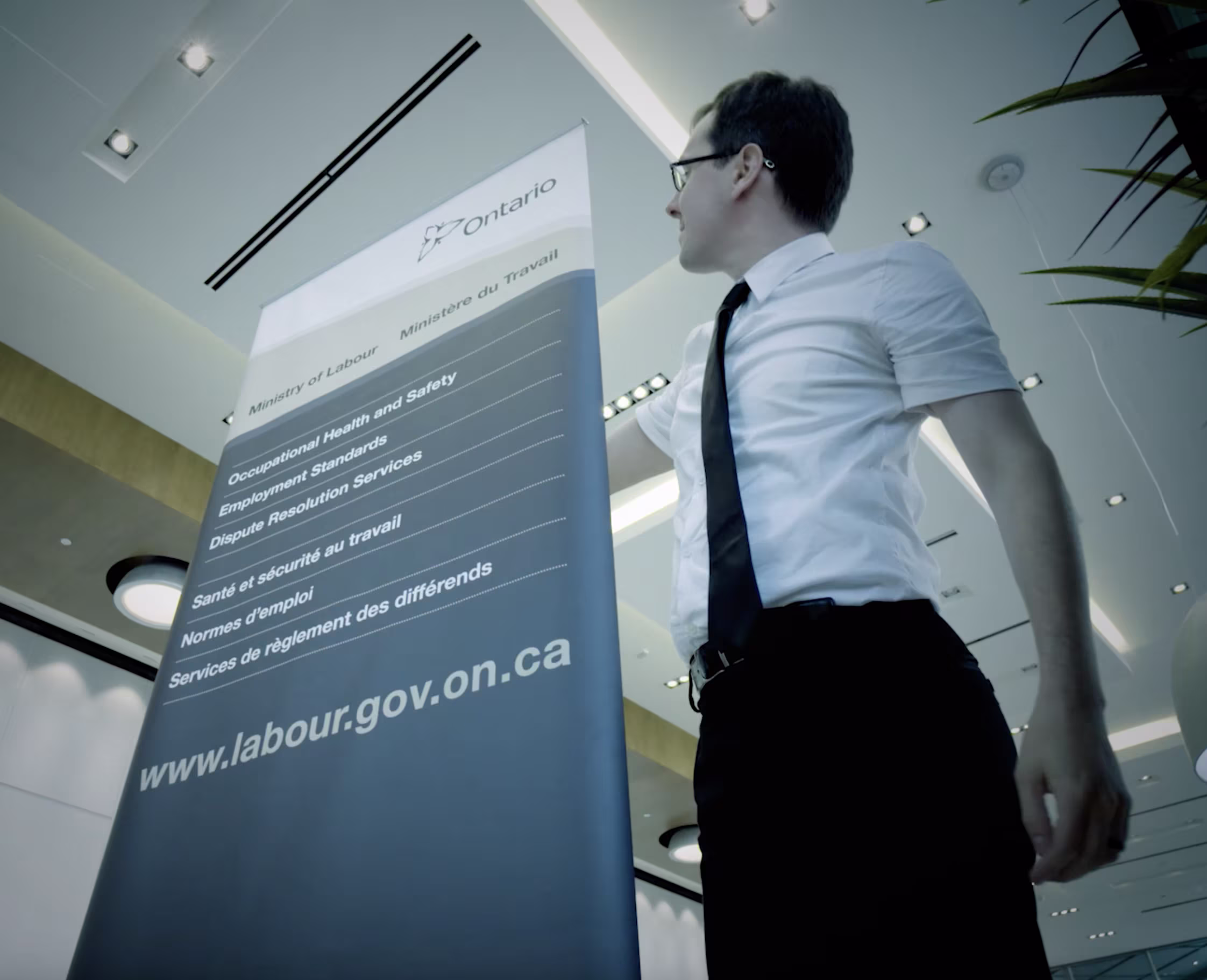 Professional standing beside a presentation screen displaying Ontario labour information in an office.